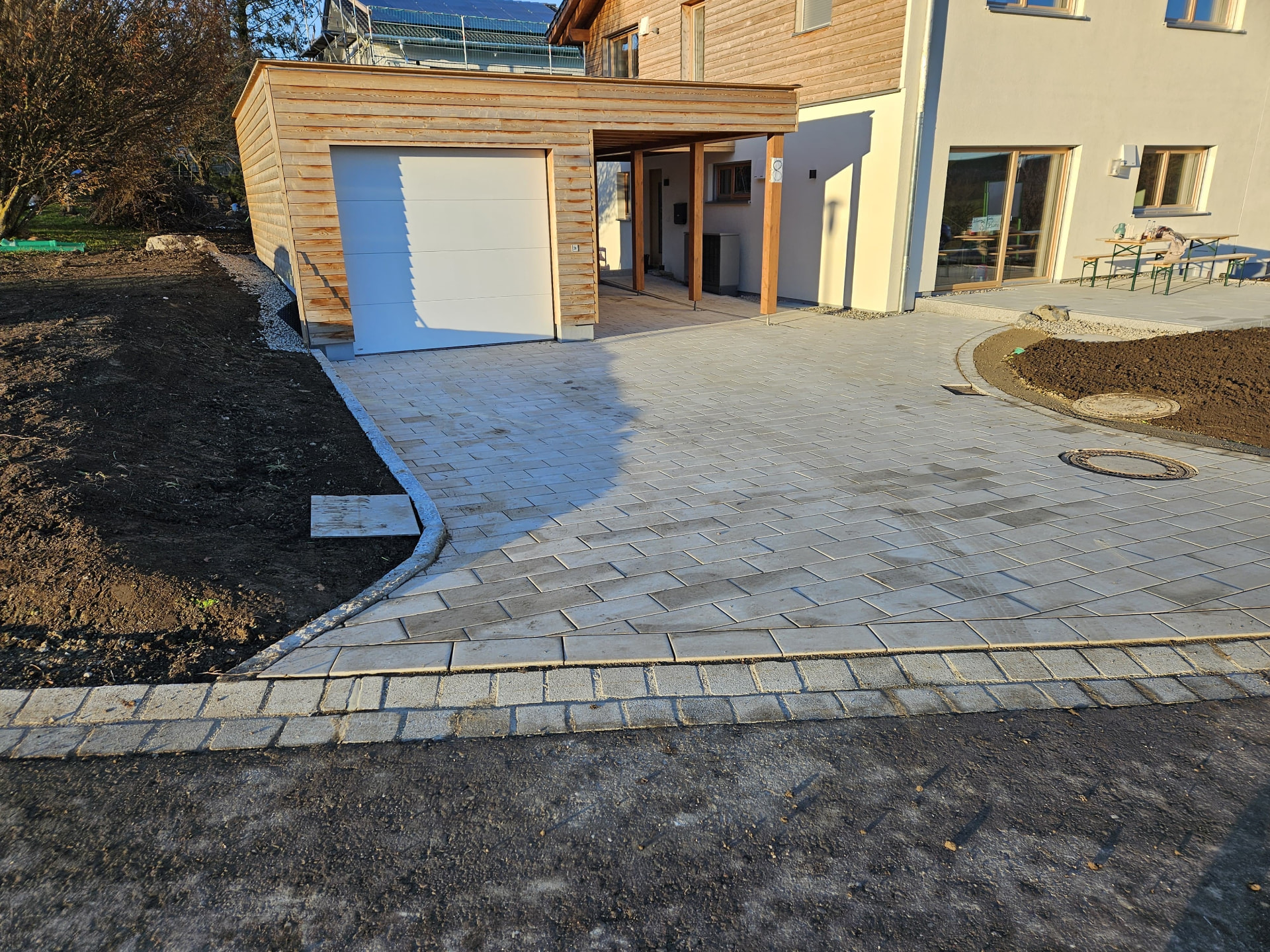 Große Pflasterfläche mit geschwungener Einfassung vor Garage und Terrasse